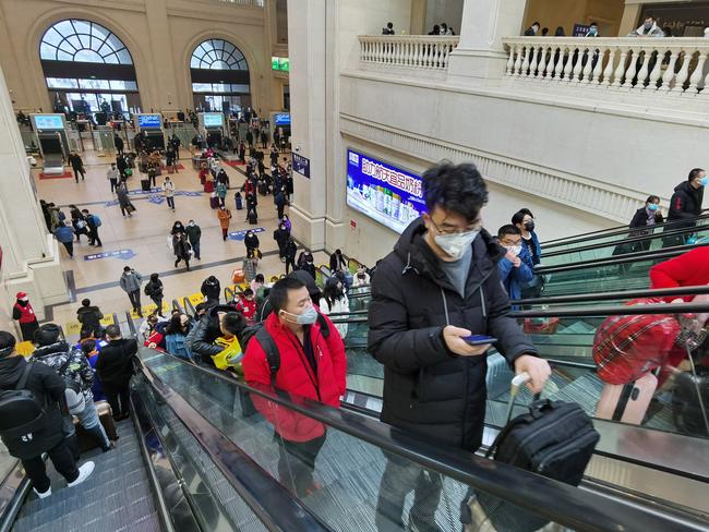 People wearing face masks ride escalators inside Hankou Railway Station. Picture: Getty Images