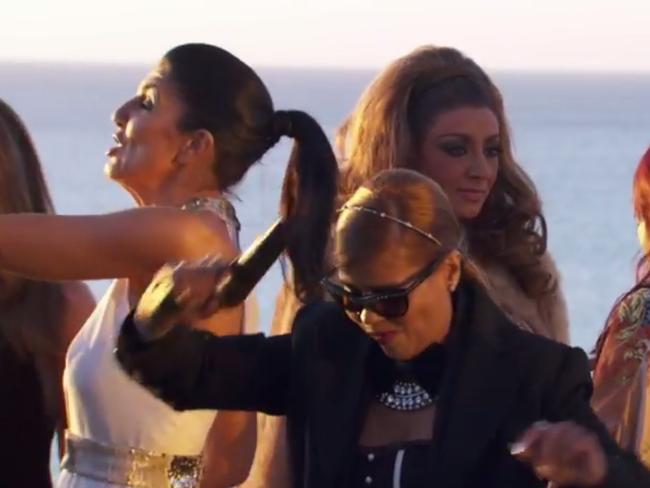 Pettifleur waves her pistol around while behind her, Gina prepares to take a flying leap into the ocean.