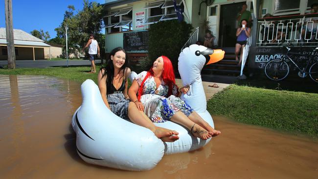 Tahlia Thomasson, 19, and Fitzroy Hotel publican Tiona McGuigan fool around in floodwater on a pool toy in front of the hotel in Depot Hill. Picture: Tim Marsden