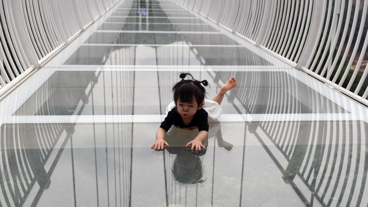 This young visitor looks like she hasn’t quite made up her mind as she crawls on the Bach Long glass bridge on its opening day last Friday. Picture: Nhac Nguyen/AFP