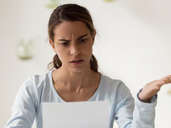 Head shot portrait stressed millennial  woman reading paper with bad news. Frowning female employee irritated by dismissal notice. Unhappy young lady disagree with false information; banking errors and mistakes generic