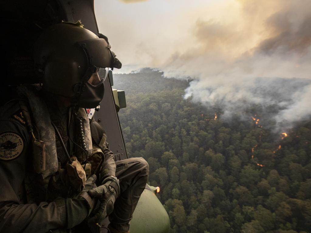 Royal Australian Navy Aircrewman Leading Seaman Ben Nixon of 808 Squadron, assesses the Tianjara Fire in the Moreton and Jerrawangala National Parks out of an MRH90 Taipan Military Support Helicopter. Picture: ADF