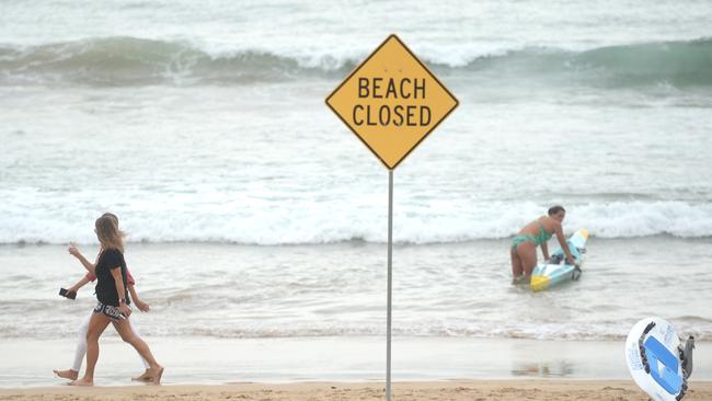 People exercise along a closed Manly Beach. It, and four other beaches, will remain closed until at least April 28. Picture: Jeremy Piper