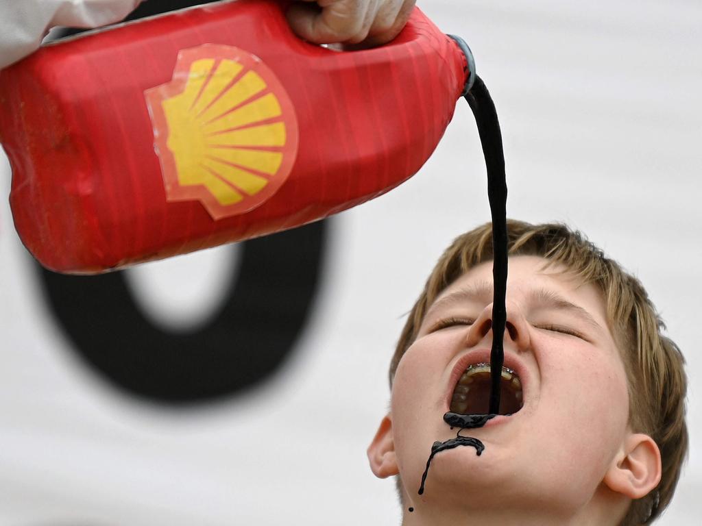 Activists from the climate change protest group Extinction Rebellion, pour a black liquid to represent oil, into the mouth of a fellow activist as they demonstrate against oil giant Shell on the beach in St Ives, Cornwall.