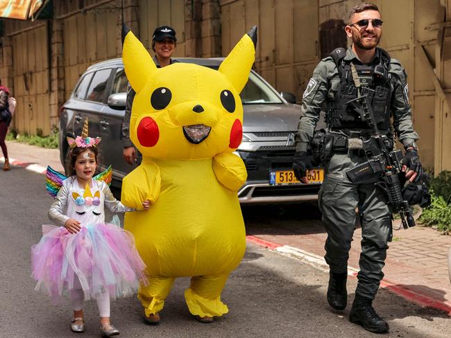 In the divided city of Hebron in the occupied West Bank, an Israeli border guard escorts Purim revellers along Al-Shuhada street, which is largely closed to Palestinians. Picture: Hazem Bader/AFP