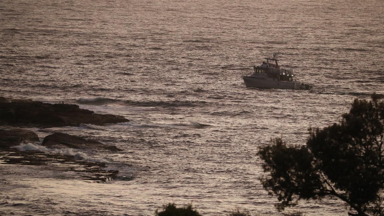 People watch as water police turn up early to search for remains. Picture: John Grainger