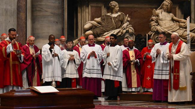 Pope Francis, right, by the coffin of Cardinal George Pell. Picture: AFP