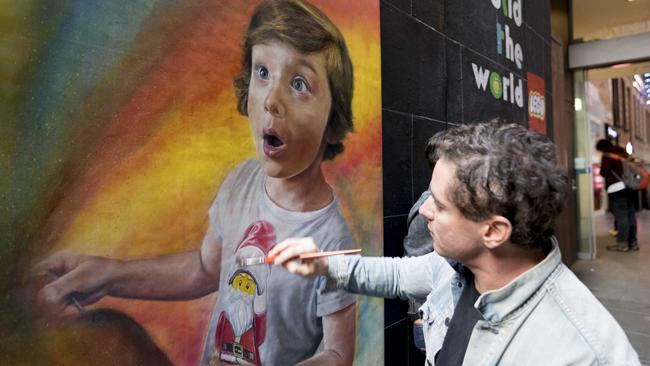 Artist Vincent Fantauzzo working on the festive mural in Knox Place near Melbourne Central