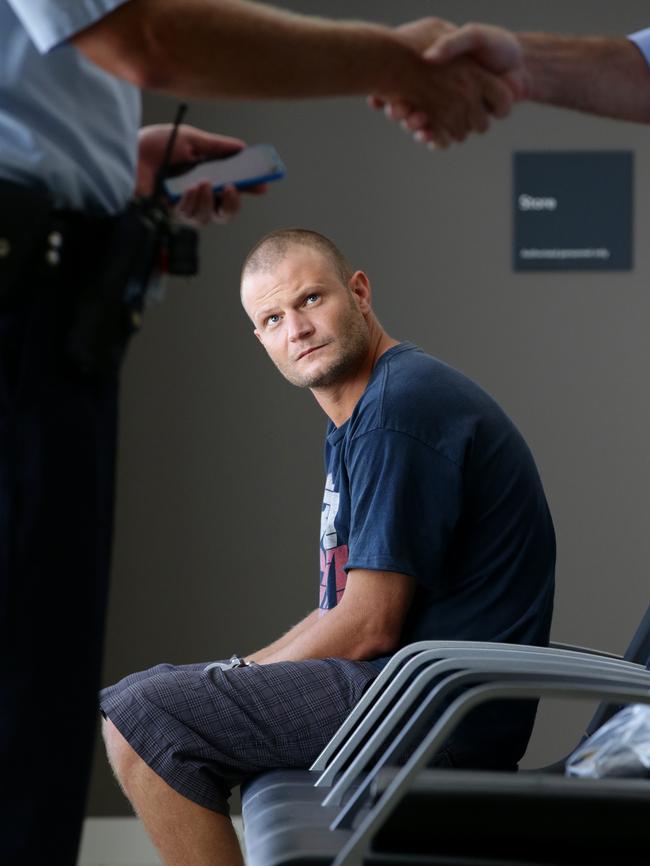 An Australian Police officer and a Victorian dectective shake hands at Cairns airport as Christopher John Lavery looks on in handcuffs. Picture: Marc McCormack