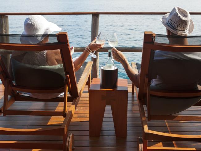 Couple relaxing on sun lounges in an over water bungalow toasting. Picture: iStock