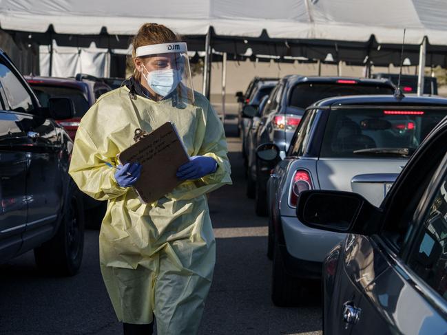 A healthcare worker walks along the lines of cars at a drive-thru Covid-19 testing site in El Paso, Texas on January 12, 2022. - The country is currently seeing an average of 750,000 cases a day -- though that figure is soon expected to exceed a million -- around 150,000 total Covid hospitalizations, and more than 1,600 daily deaths. (Photo by PAUL RATJE / AFP)