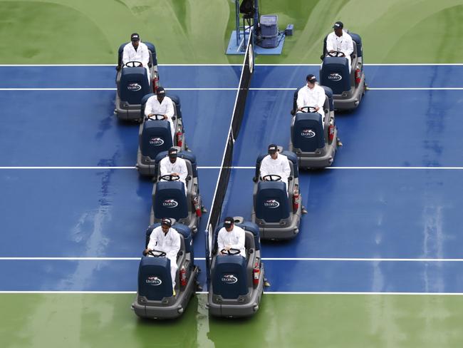 Court maintenance crew workers drive dryers over the court at Arthur Ashe Stadium during a rain delay during the semifinals of the 2014 U.S. Open tennis tournament, Saturday, Sept. 6, 2014, in New York. (AP Photo/Julio Cortez)