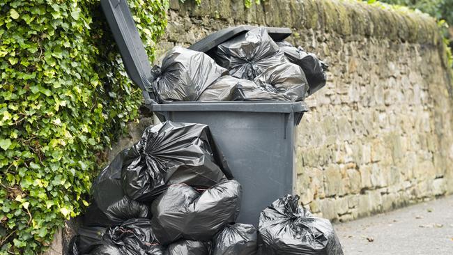 A full wheelie bin with rubbish bags overflowing onto the pavement. Picture: File