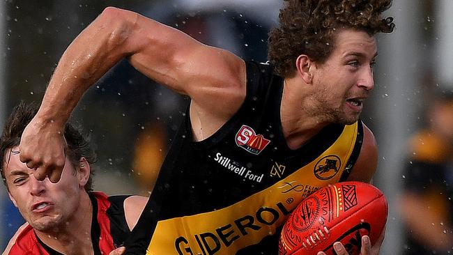 Glenelg's Matthew Snook gets the ball under pressure from West's Joshua Schiller as the rain comes down at the Bay. .Picture: Mark Brake