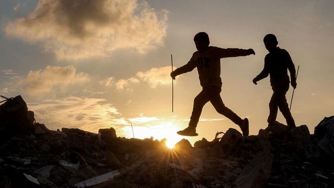 Boys walk atop a mound of rubble at a camp for people displaced by conflict in Bureij in the central Gaza Strip following the announcement of a truce. Picture: AFP