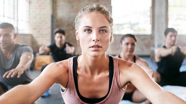 Shot of a group of people doing squats in a gym