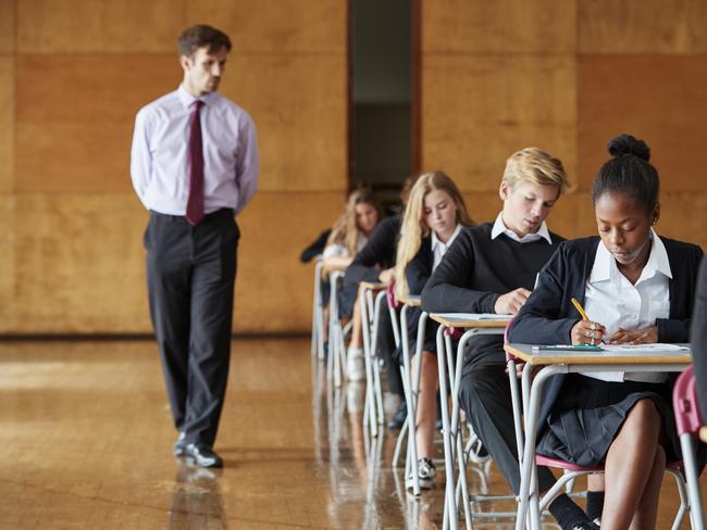 A teacher watching students undertake an examination.