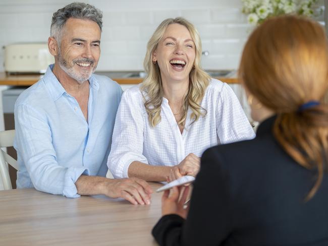 Happy mature couple meeting investments and financial advisor at home. They are happy and smiling. The agent is holding a digital tablet.  Planner advice generic