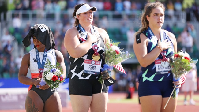 Gwen Berry, left, standing in third place on the podium with her shirt on covering her head while the US national anthem played. Photo by Patrick Smith/Getty Images