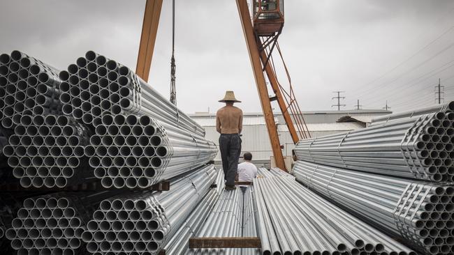 Workers prepare to lift bundles of steel pipe with a crane at a stockyard on the outskirts of Shanghai, China. Picture: Qilai Shen/ Bloomberg.