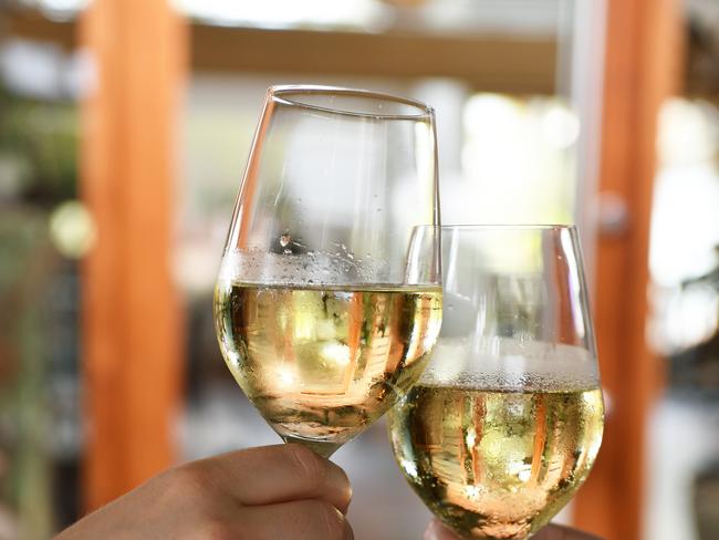 A man and womans hands 'cheers' a glass of wine