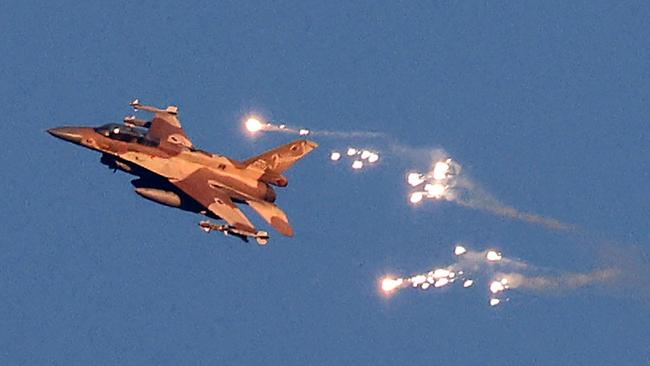 This photo taken from a position in northern Israel shows an Israeli Air Force fighter jet firing flares as it flies to intercept a hostile aircraft that launched from Lebanon over the border area with south Lebanon on August 25, 2024. The Israeli military announced early August 25, 2024 that it was conducting pre-emptive strikes in Lebanon after detecting preparations for "large-scale" attacks by the Iran-backed militant group Hezbollah. Hezbollah said August 25, 2024 it had launched more than 320 rockets at Israel overnight, targeting a string of military positions, even as Israel's military said it was carrying out pre-emptive strikes against the group. (Photo by Jalaa MAREY / AFP)