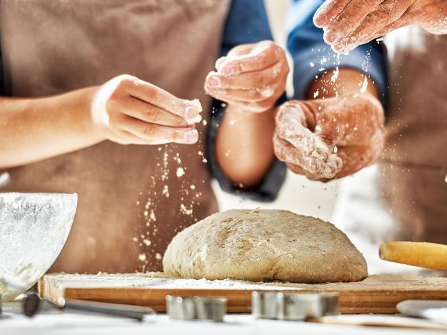 Close up view of bakers are working. Homemade bread. Hands preparing dough on wooden table. Picure: Istock