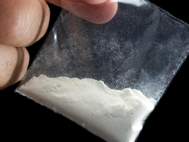 Generic photo of cocaine. Dealer is holding drug bag in his hand on a black background. Picture: iStock