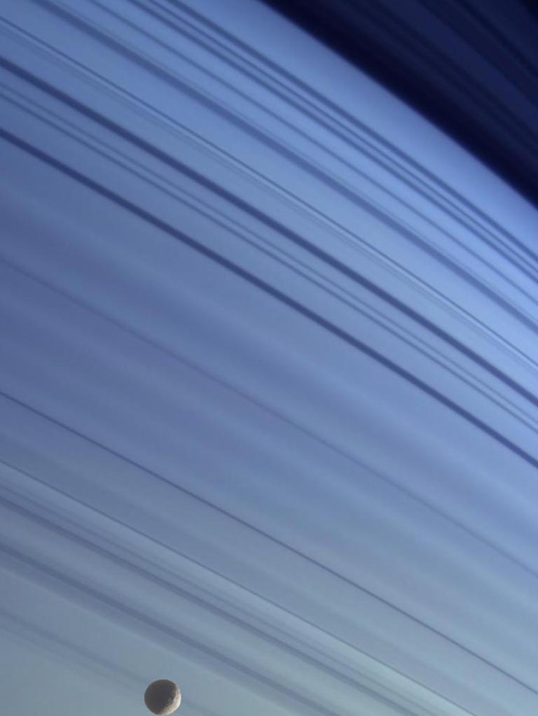 At the bottom of this 2005 image, Mimas can be seen drifting along in its orbit against the blue backdrop of Saturn's northern latitudes in this true colour view released by NASA. The long, dark lines on the atmosphere are shadows cast by the planet's rings. Picture: AFP Photo/NASA