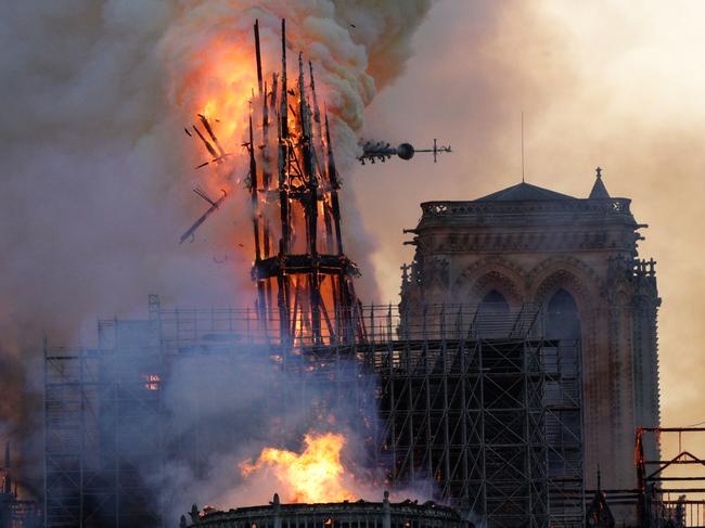 TOPSHOT - The steeple collapses as smoke and flames engulf the Notre-Dame Cathedral in Paris on April 15, 2019. - A huge fire swept through the roof of the famed Notre-Dame Cathedral in central Paris on April 15, 2019, sending flames and huge clouds of grey smoke billowing into the sky. The flames and smoke plumed from the spire and roof of the gothic cathedral, visited by millions of people a year. A spokesman for the cathedral told AFP that the wooden structure supporting the roof was being gutted by the blaze. (Photo by Geoffroy VAN DER HASSELT / AFP)