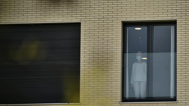 A woman wearing a face mask looks on through the window at the San Martin nursing home in Vitoria, northern Spain. Picture: AP