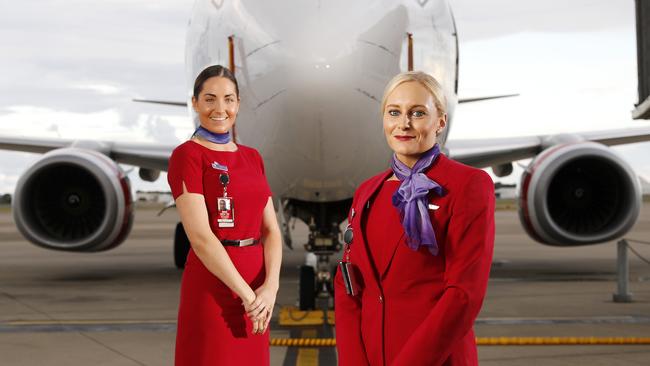 Virgin staff Alahna Wilkinson and Alice Whittle posing in front of Long Beach, 737-800 at Brisbane Airport this month. Picture: AAP