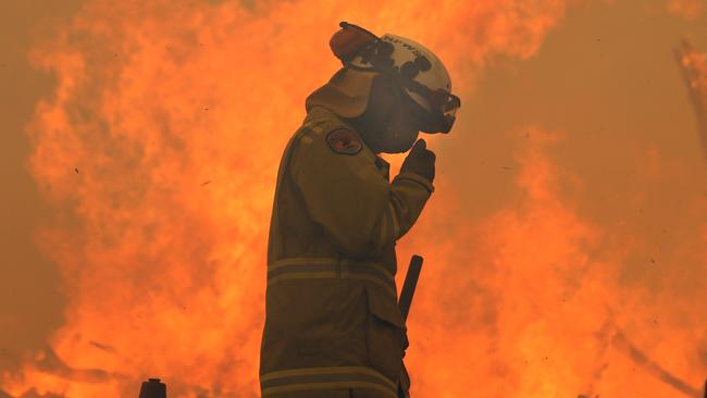 This firefighter was surrounded by flames as he worked to protect a home at Termeil. Picture: Gary Ramage