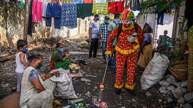 Ashok Jagannath Kurmi, a 36-year-old social worker, sprays disinfectant liquid while dressed in a clown costume at a slum in Mumbai, India. He dresses in different costumes during his outreach to help spread official messages about COVID-19. Picture: Fariha Farooqui/Getty Images