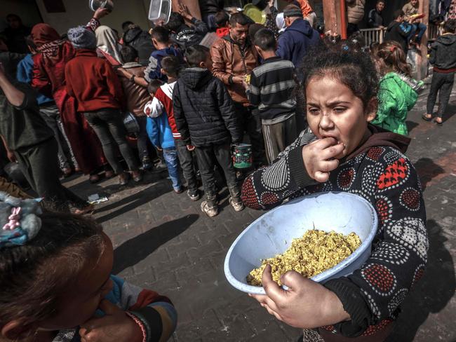 Displaced Palestinian children gather to receive food at a government school in Rafah. (Photo by MOHAMMED ABED / AFP)