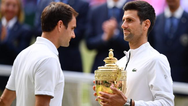 Novak Djokovic, right, holds the winner's trophy as he passes vanquished foe Roger Federer during the trophy (L) during the Wimbledon presentation. Picture: AFP