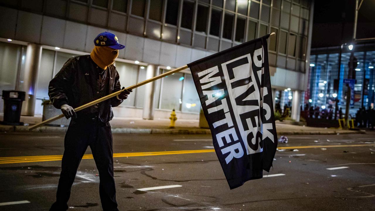 A protester wearing a Black Panther jacket and holding a Black Lives Matter flag faces off with riot police in Rochester, New York, on September 5, 2020. Picture: Maranie R. Staab/AFP