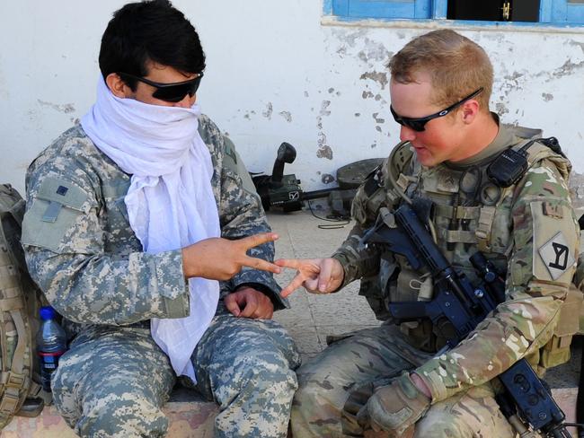 A Shura or meeting at Chora, Afghanistan. An Afghan interpreter learns to play rock, scissor, paper with CPL Michael Wilcox from the Virginia National Guard in the administration building in Chora, Afghanistan.