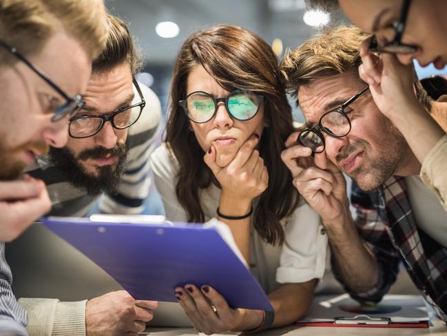 Group of thoughtful business people with eyeglasses reading documents in the office. Confused millenials