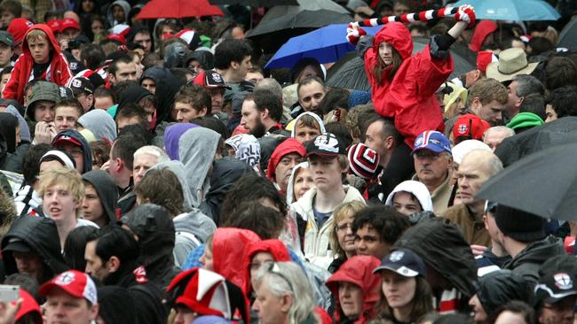 Fans brave the wet conditions during the 2009 AFL Grand Final Parade through the streets of Melbourne. Picture: HWT Library.