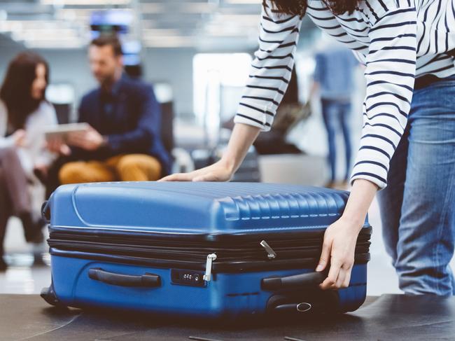 Young woman passenger collecting her luggage from conveyor belt. Female traveler picking up suitcase from baggage claim line in airport terminal.Escape 14 January 2024Kendall HillPhoto - iStock