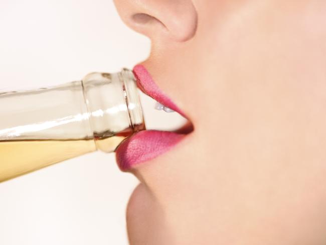 Close-up profile view of a woman's lips drinking from a bottled beer