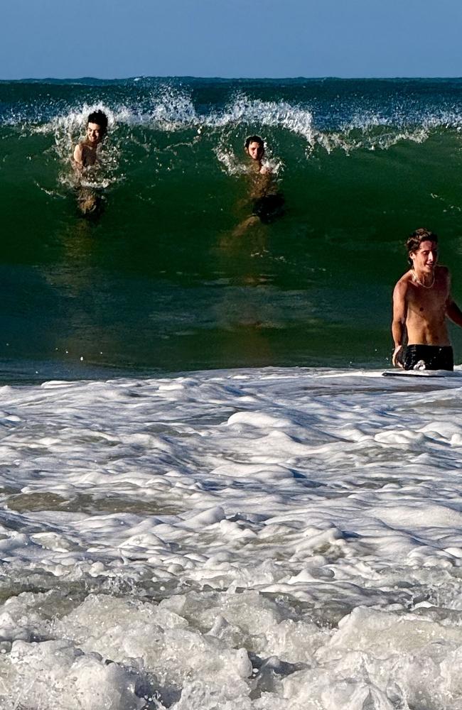 Swimmers check out the big surf ahead of a dumping wave on low tide at Mooloolaba. Photo: Mark Furler