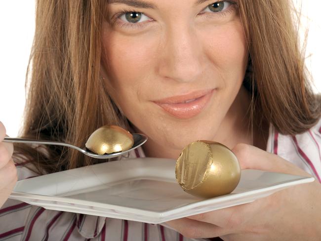 Your Money superannuation generic images. Woman eating golden nest egg with spoon from plate.