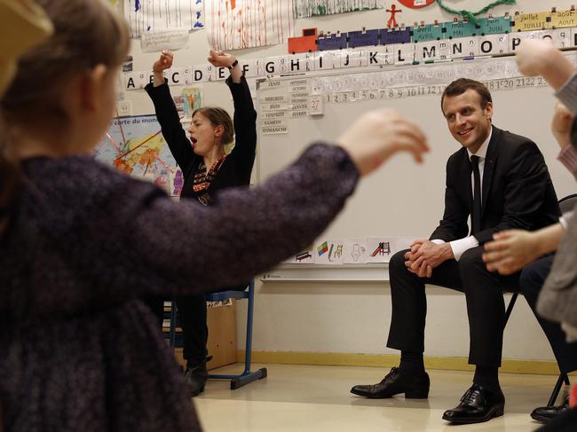 French President Emmanuel Macron, center, listens to pre-school children as he visits the Emelie pre-school in Paris, Tuesday, March 27, 2018. Macron's government wants to require all French children to attend pre-school starting at age 3 as part of broader educational reforms aimed at reducing inequalities. (AP Photo/Christophe Ena)