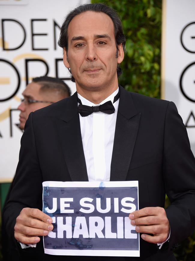 Composer Alexandre Desplat holds up a sign as a tribute to Paris.