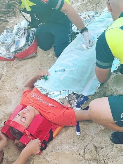 Ironwoman champion Georgia Miller being attended to on the beach. Picture: Instagram