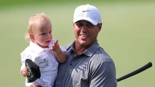 Brooks Koepka of the United States smiles with his son, Crew Sims. Koepka has been one of golf’s most formidable players in recent years, known for his powerful game and mental toughness. Picture: Getty