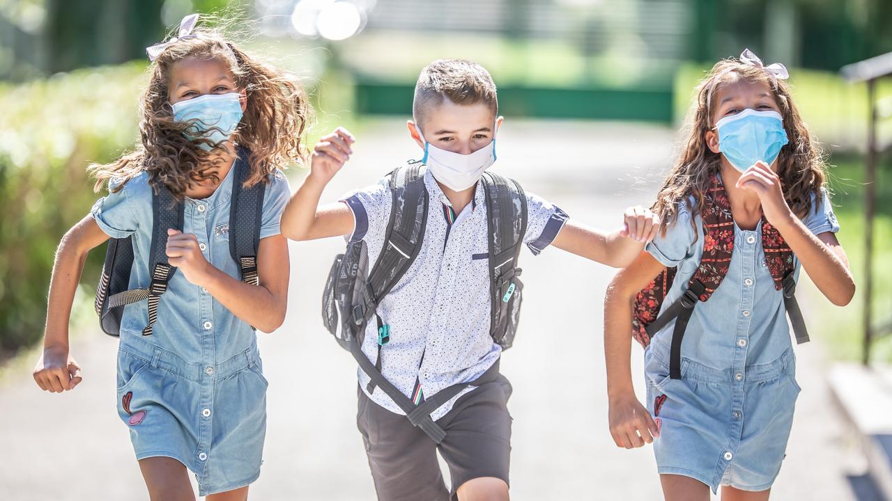 Happy schoolchildren with face masks run from the joy of returning to school during the Covid-19 quarantine.