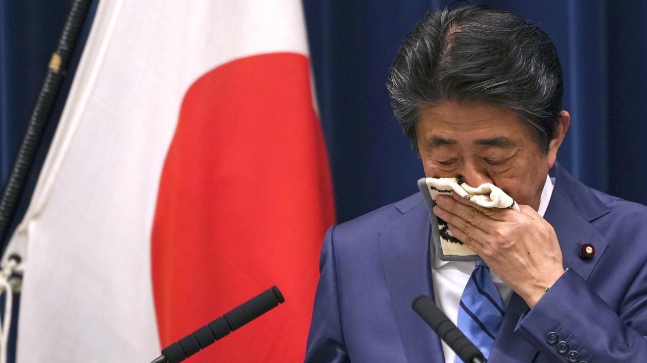 Japanese Prime Minister Shinzo Abe wipes his face as he answers a question.